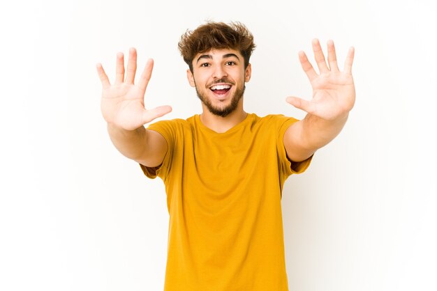 Young arab man on white background showing number ten with hands.