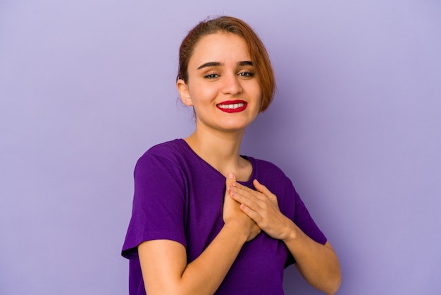 Young arab mixed race woman has friendly expression, pressing palm to chest. Love concept.