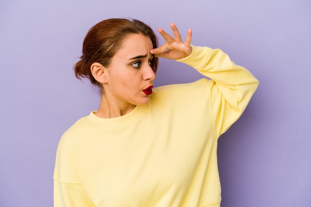 Young arab mixed race woman looking far away keeping hand on forehead.