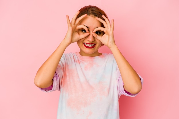 Young arab mixed race woman showing okay sign over eyes