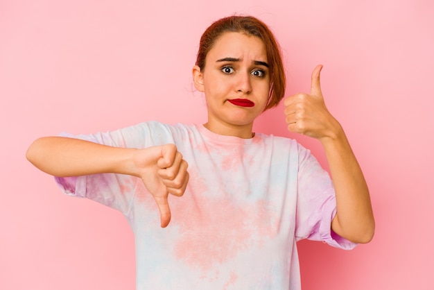 Young arab mixed race woman showing thumbs up and thumbs down, difficult choose concept