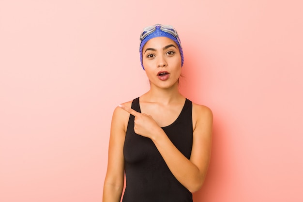 Young arab swimmer woman isolated pointingthe side