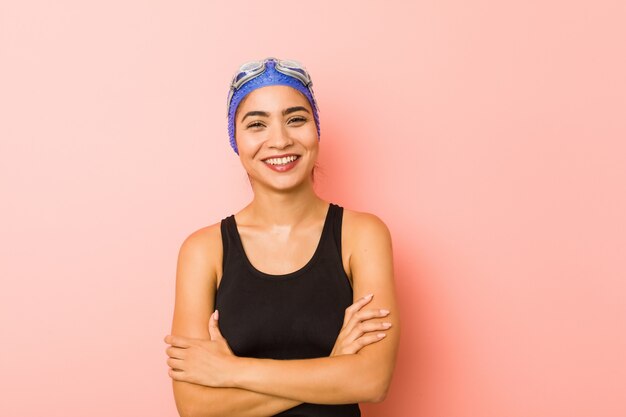 Young arab swimmer woman isolated who feels confident, crossing arms with determination.