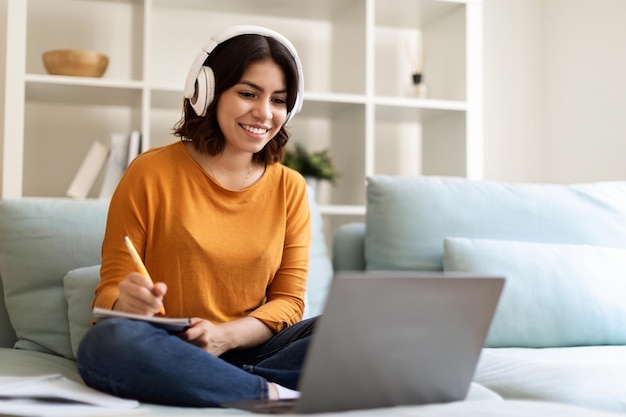 Foto giovane donna araba in cuffia studia online con il computer portatile da casa