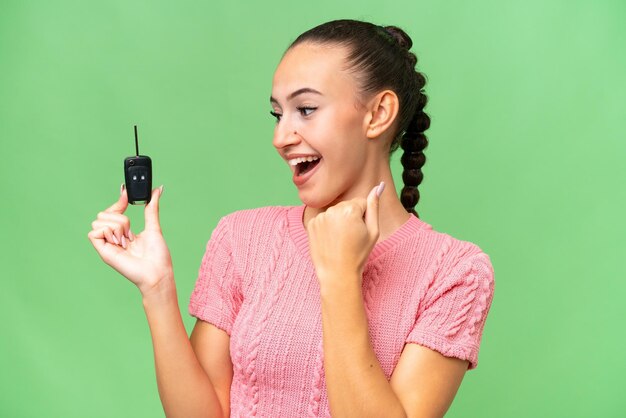 Young Arab woman holding car keys over isolated background celebrating a victory