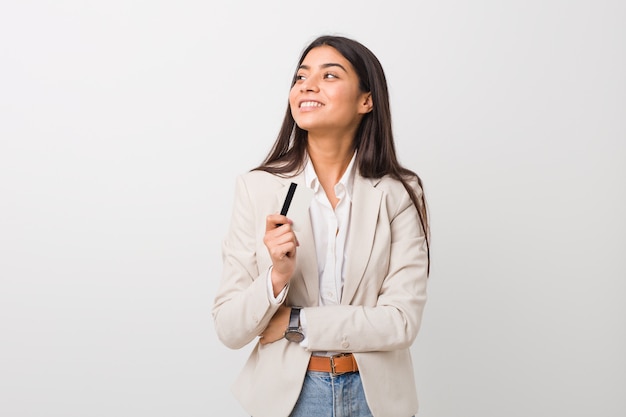 Young arab woman holding a credit card smiling confident with crossed arms.