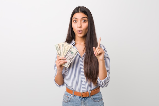 Young arab woman holding dollars having some great idea, concept of creativity.