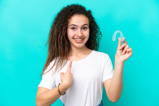 Photo young arab woman holding invisible braces isolated on blue background with surprise facial expression