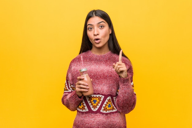 Young arab woman holding a smoothie having some great idea, concept of creativity.