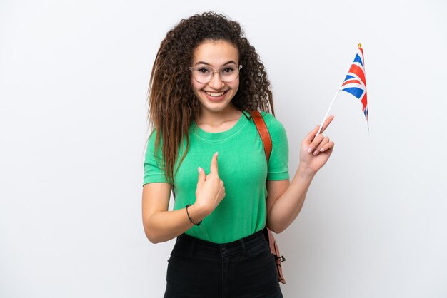 Young arab woman holding an united kingdom flag isolated on\
white background with surprise facial expression