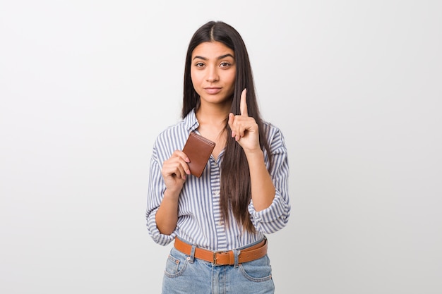 Young arab woman holding a wallet showing number one with finger.