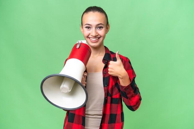 親指を立ててメガホンを持っている孤立した背景の上の若いアラブ女性