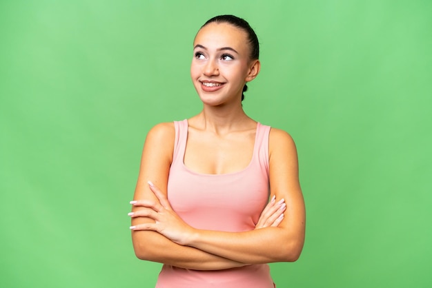Young Arab woman over isolated background looking up while smiling