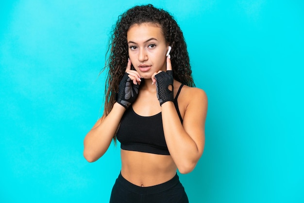 Young arab woman isolated on blue background listening music and looking to the front