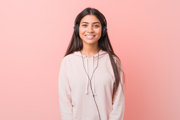 Young arab woman listening to music happy, smiling and cheerful.