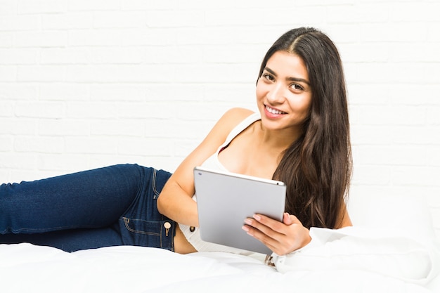 Young arab woman lying on the bed using a tablet