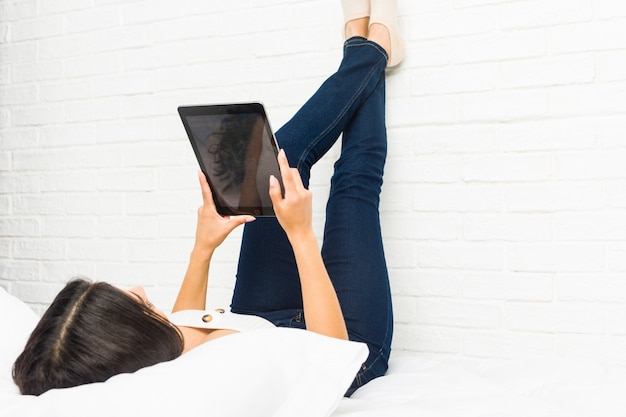 Young arab woman lying on the bed using a tablet