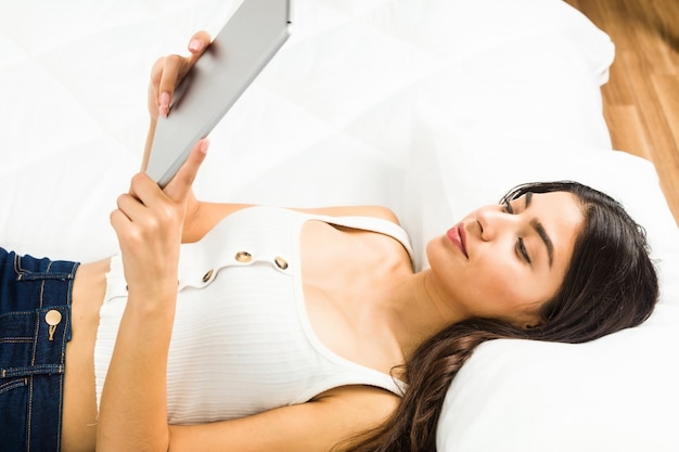 Young arab woman lying on the bed using a tablet