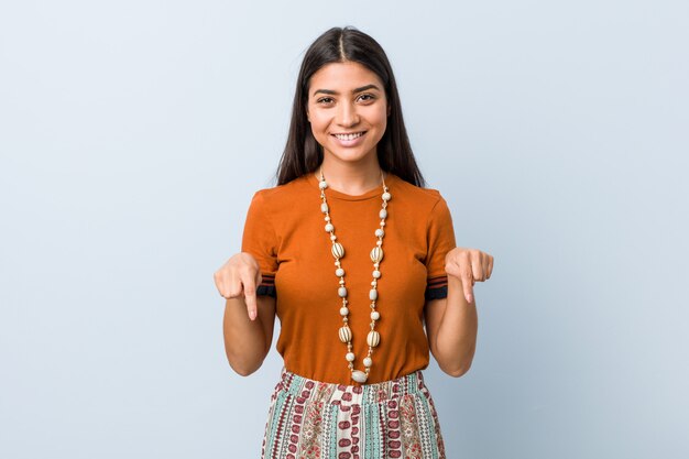 Young arab woman points down with fingers, positive feeling.