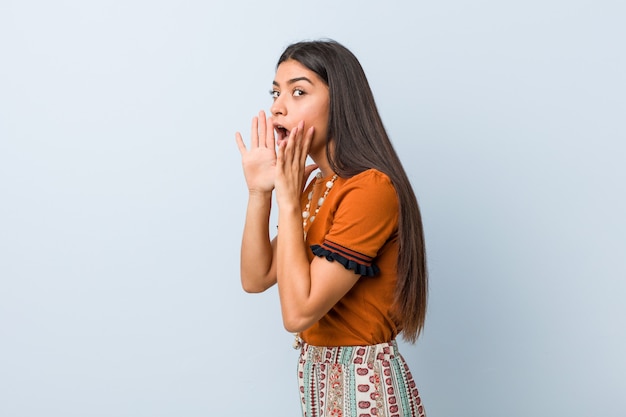 Young arab woman shouts loud, keeps eyes opened and hands tense.