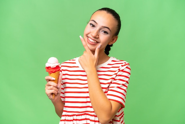 孤立した背景に幸せと笑顔でコルネット アイス クリームを持つ若いアラブ女性