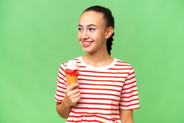 Young Arab woman with a cornet ice cream over isolated background looking to the side and smiling