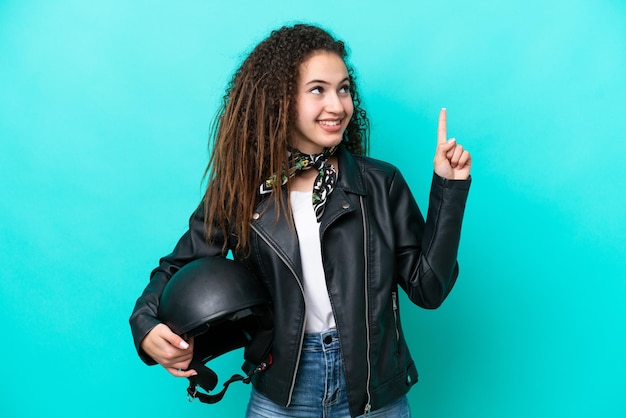 素晴らしいアイデアを指している青い背景に分離されたオートバイのヘルメットを持つ若いアラブの女性