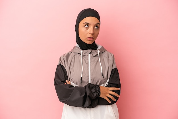 Young Arab woman with sport burqa isolated on pink background tired of a repetitive task.