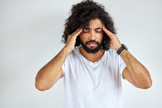 Young arabian indian guy with long hair has head ache