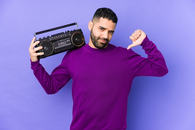 Young arabian man holding a radio cassette isolated Young arabian man listening music feels proud and self confident, example to follow.