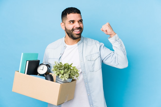 Young arabian man moving to a new home raising fist after a victory