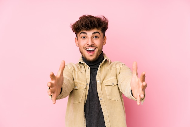 Young arabian man posing in a wall isolated feels confident giving a hug to the camera.