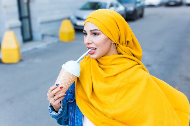 Giovane donna musulmana araba che gode del cocktail all'aperto.