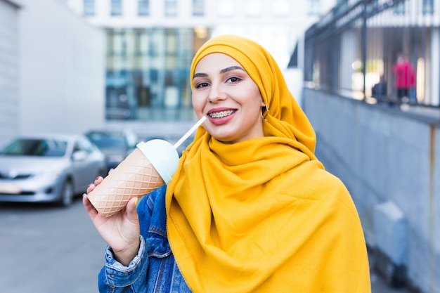 屋外でカクテルを楽しんでいる若いアラビアのイスラム教徒の女性。