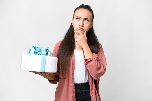 Young Arabian woman holding birthday cake over isolated white background having doubts