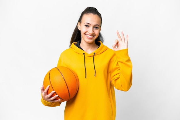 Young Arabian woman playing basketball over isolated white background showing ok sign with fingers