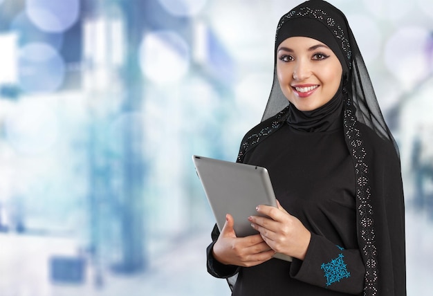 Молодая аравийская женщина с планшетом на размытом фоне