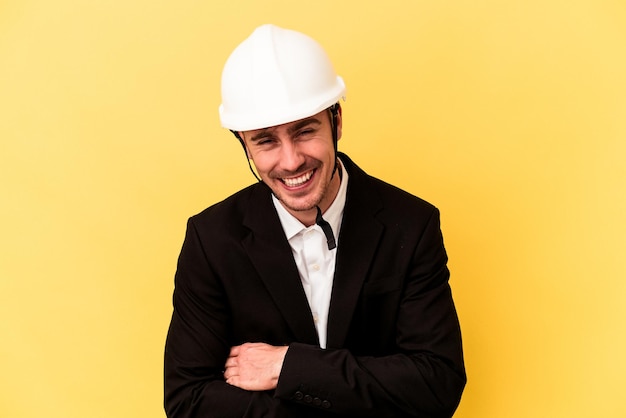 Young architect caucasian man isolated on yellow background laughing and having fun.