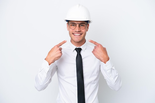 Молодой архитектор кавказец в шлеме и держит чертежи на белом фоне, показывая большой палец вверх жестом