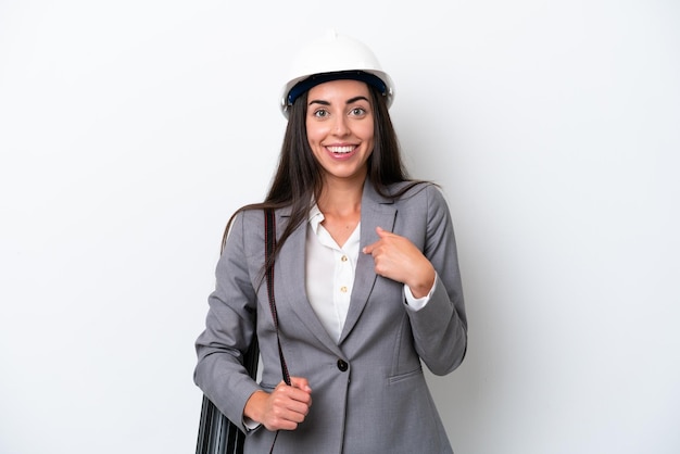 Young architect caucasian woman with helmet and holding blueprints isolated on white background with surprise facial expression