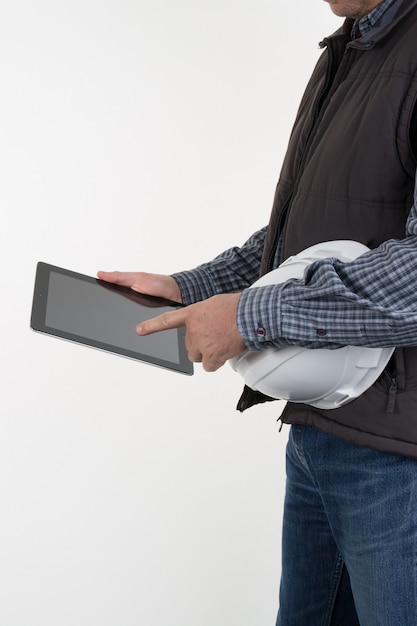 Young architect or engineer doing an inspection making comparisons against information on his tablet computer