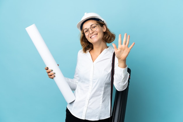 Young architect Georgian woman with helmet and holding blueprints over isolated background counting five with fingers