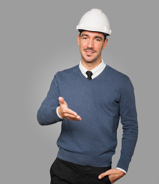 Young architect making a gesture of welcoming with his hand