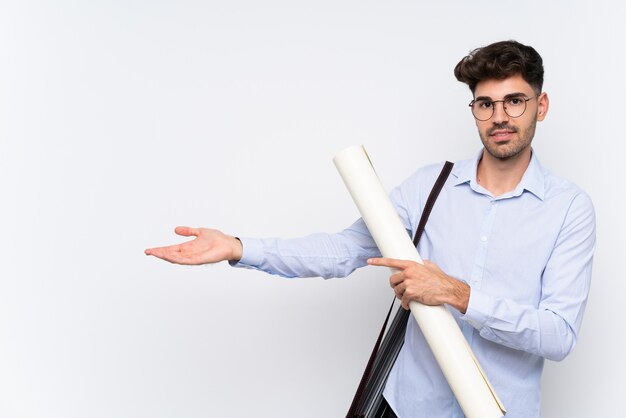 Young architect man over isolated white wall extending hands to the side for inviting to come