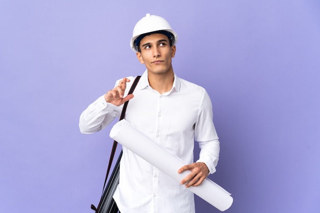 Young architect man isolated with fingers crossing and wishing the best