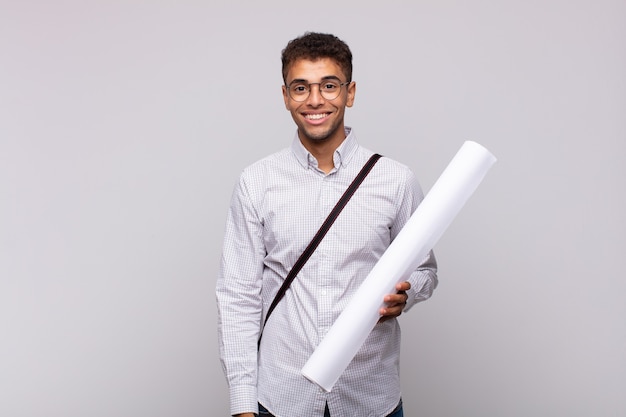 Young architect man looking happy and pleasantly surprised, excited with a fascinated and shocked expression