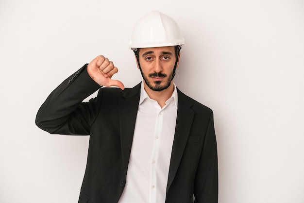 Young architect man wearing a construction helmet isolated on white background showing a dislike gesture thumbs down Disagreement concept