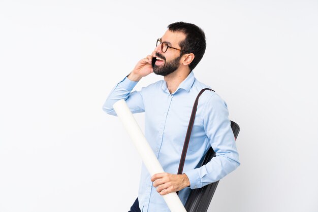 Young architect man with beard over isolated  keeping a conversation with the mobile phone