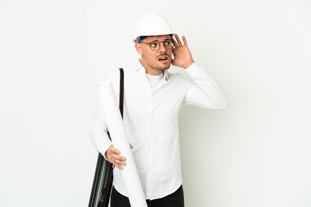 Young architect man with helmet and holding blueprints isolated