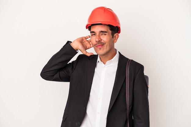 Young architect mixed race man isolated on white background touching back of head, thinking and making a choice.